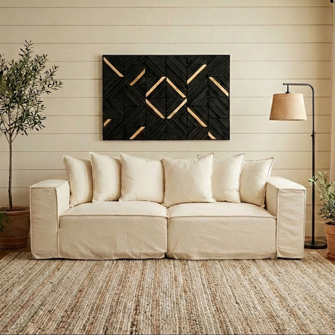 Beige sofa in a living room with decorative wall art, plants, and a lamp.