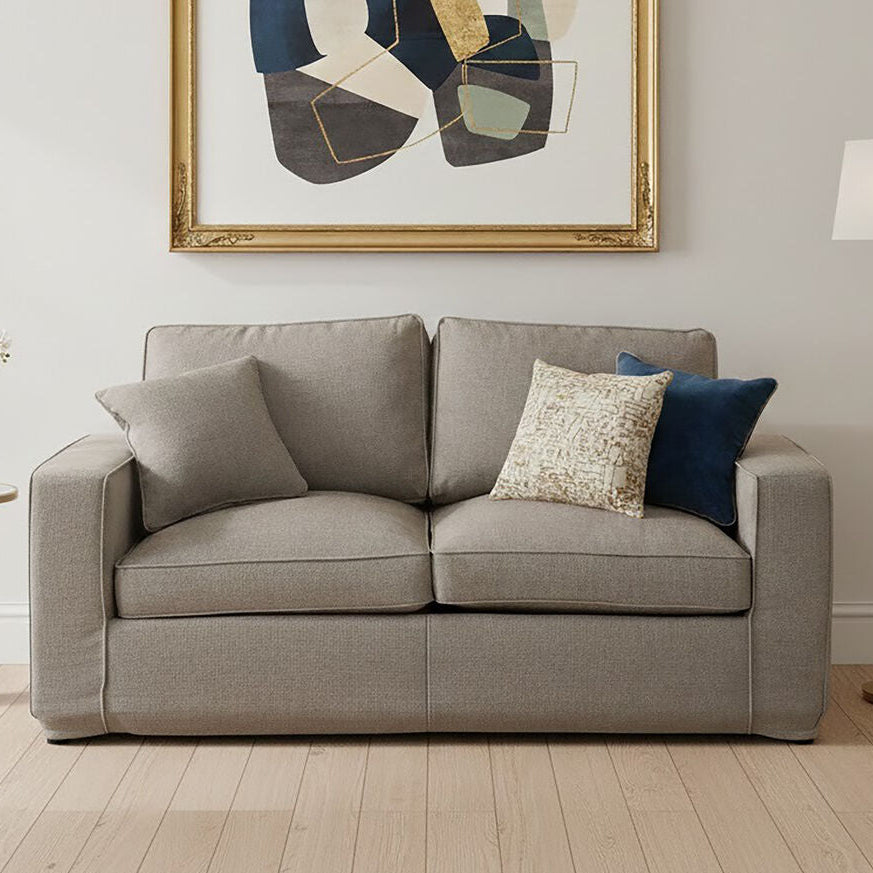 Gray sofa with decorative pillows in a living room setting with abstract art and lamp.