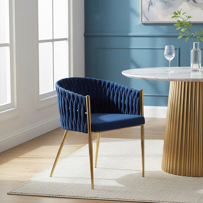 Navy blue chair with gold legs next to a round marble table in a room with blue walls and large windows.