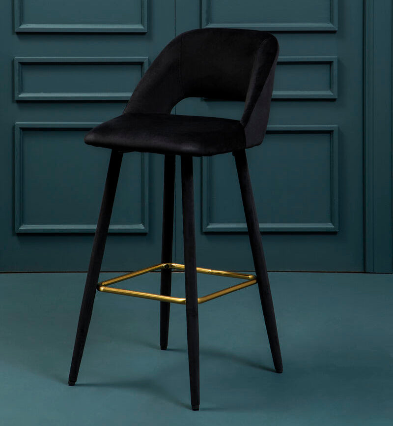 Black bar stool with gold accents against a teal paneled wall