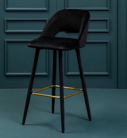 Black bar stool with gold accents against a teal paneled wall