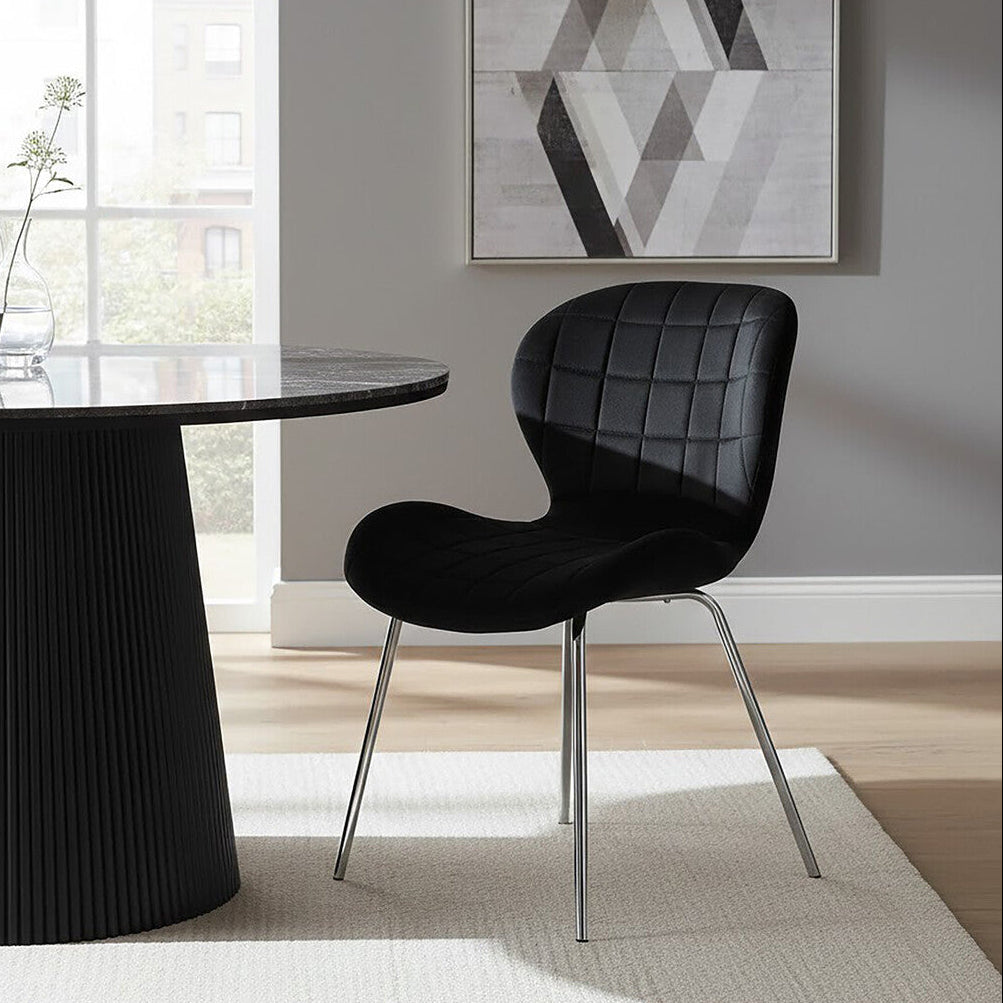 Modern black dining chair in front of a round black table with a geometric abstract painting on the wall.