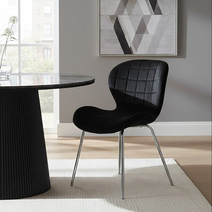 Modern black dining chair in front of a round black table with a geometric abstract painting on the wall.