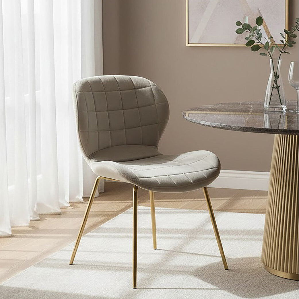 Modern chair with gold legs in a stylish room with a table and decor.