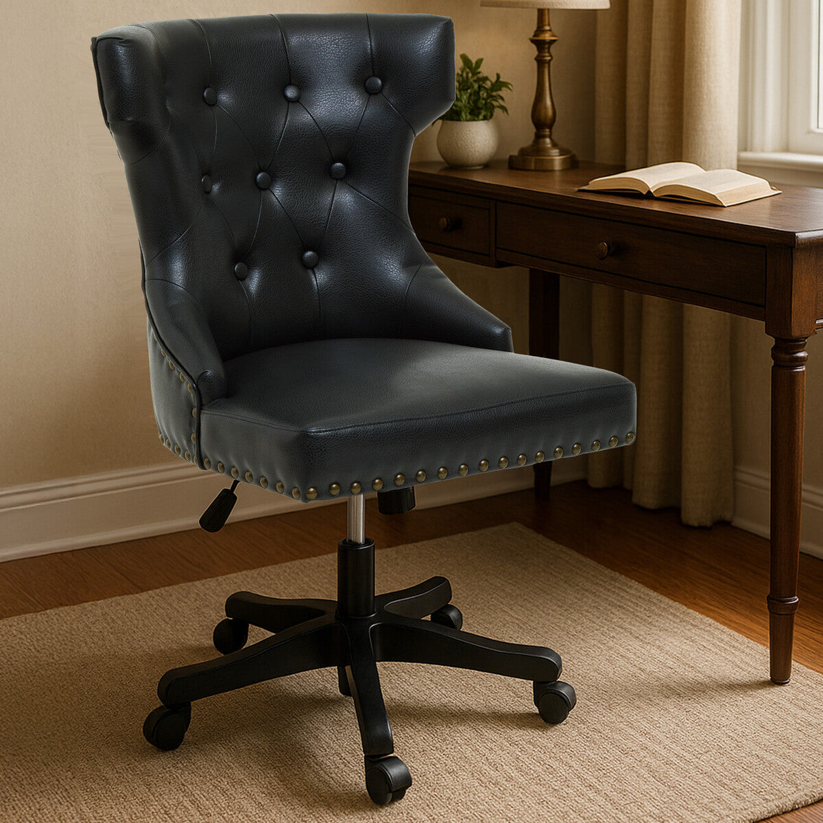 Black office chair in front of a wooden desk with a lamp and book.