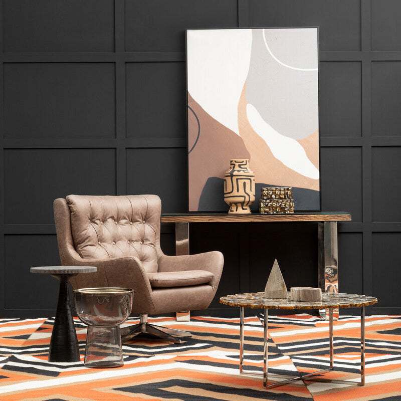 Modern interior with a beige armchair, coffee table, and abstract painting against a black paneled wall.