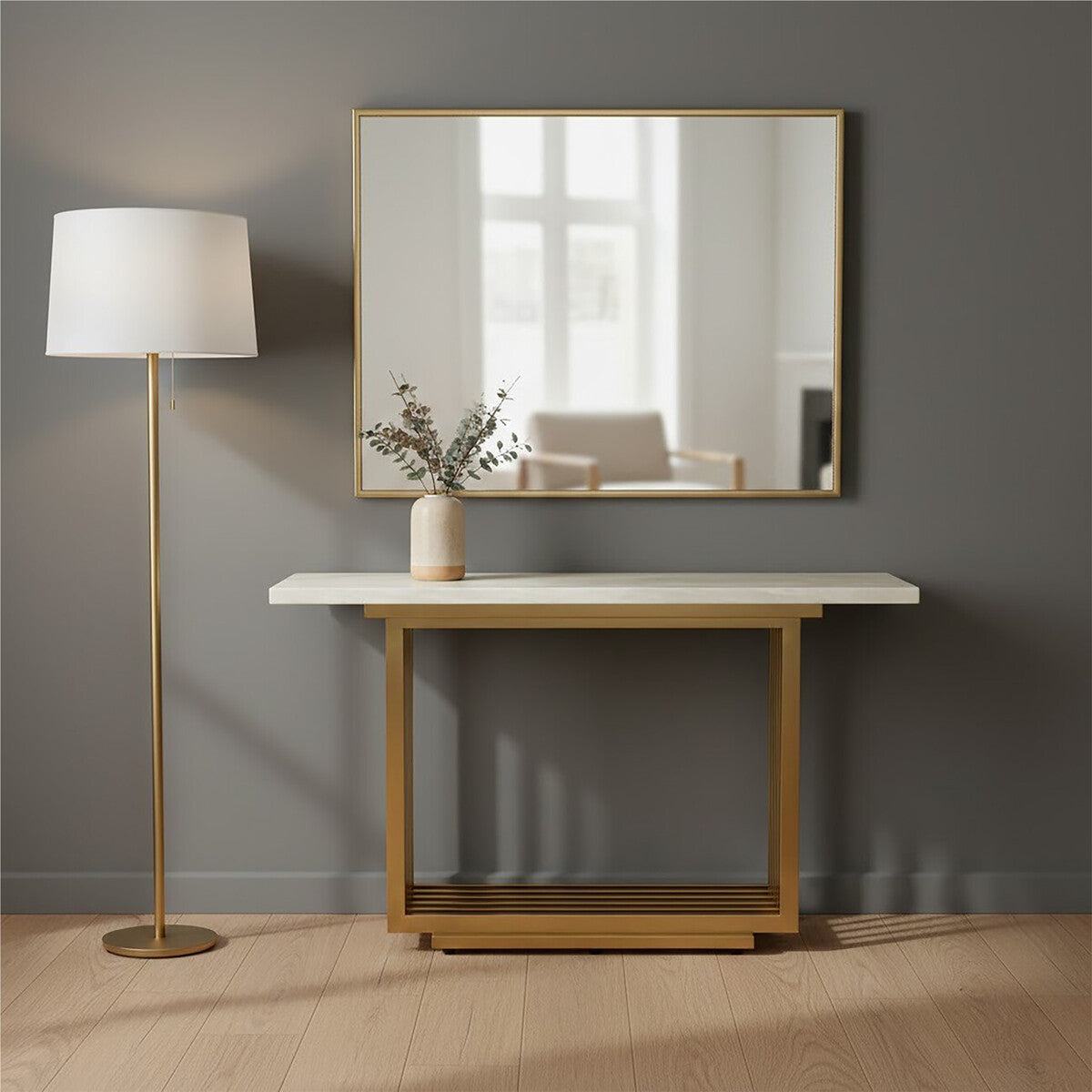Console table with marble top and gold frame next to a floor lamp against a gray wall.