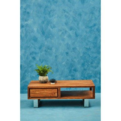 Wooden coffee table with decorative items against a blue textured wall.