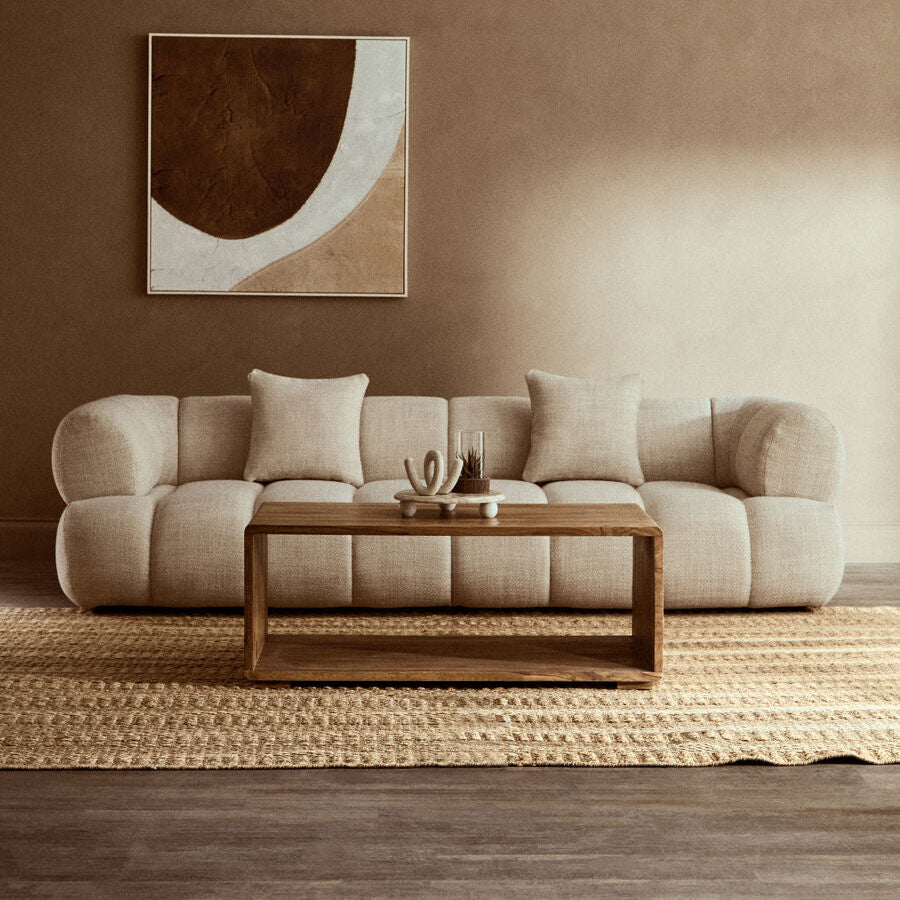 Beige sofa in a living room with a abstract painting on the wall.
