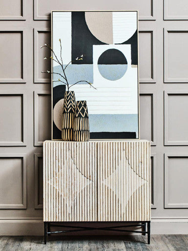 Cabinet with decorative vase and abstract art against a paneled wall