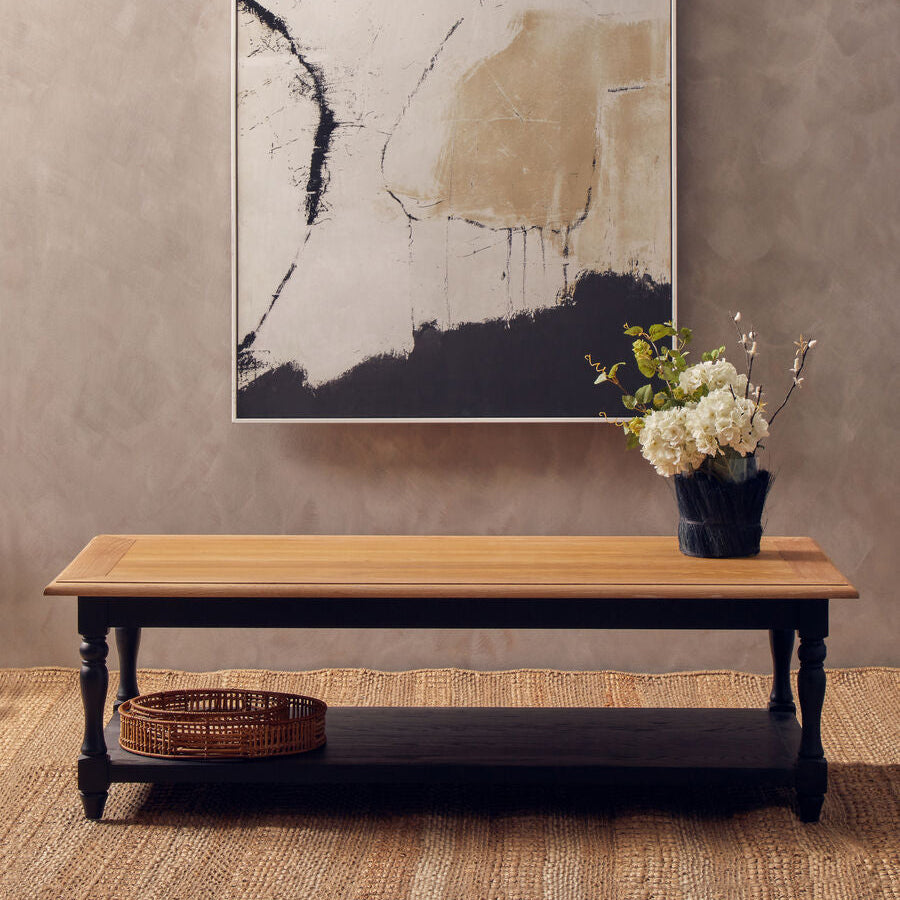 Abstract painting on a wall above a wooden table with a vase of flowers.