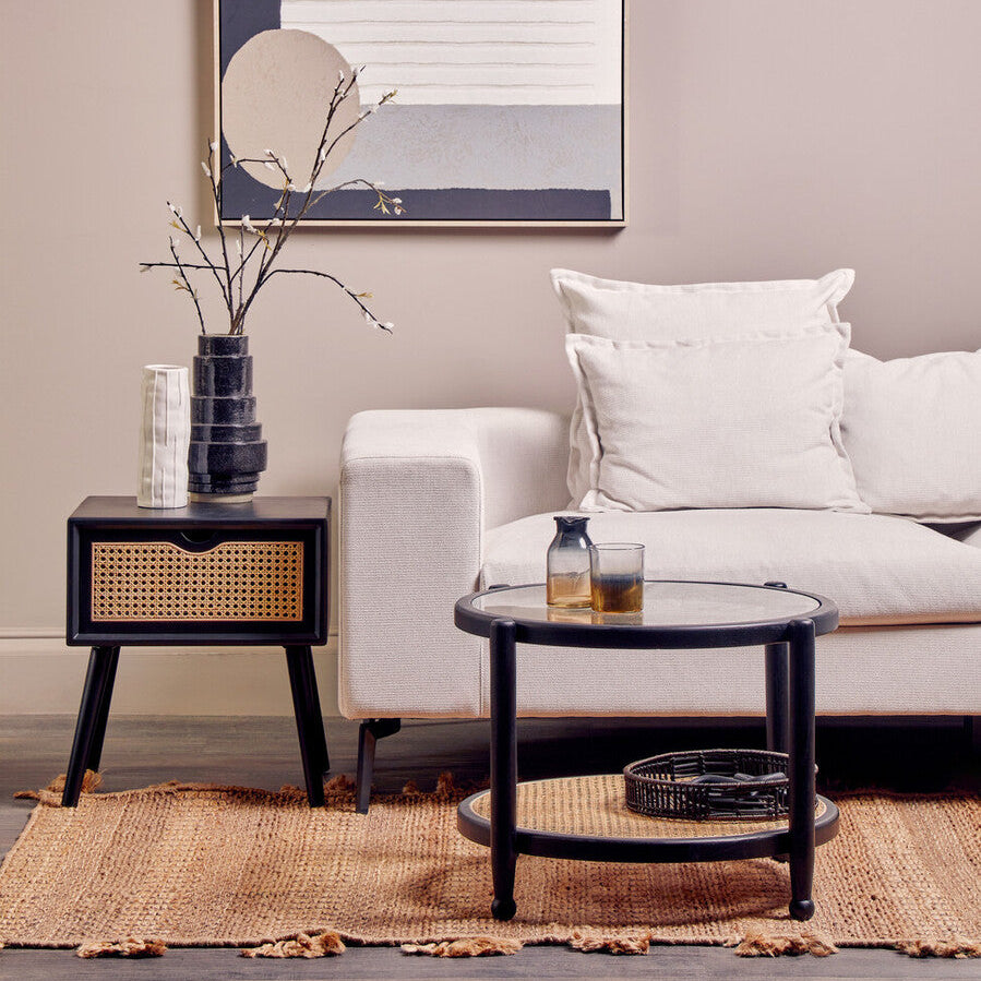 Living room with a white sofa, black coffee table, and abstract wall art.