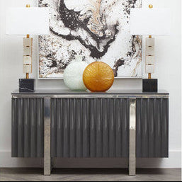 Modern console table with abstract art and decorative items against a white wall.