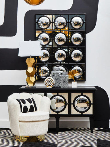 Decorative console table with mirror effect, white chair, and stylish decor items against a black and white patterned wall.