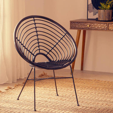 Black wire chair in a room with a wooden side table and decorative items.