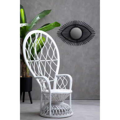 White peacock chair in a room with a plant and decorative wall mirror.