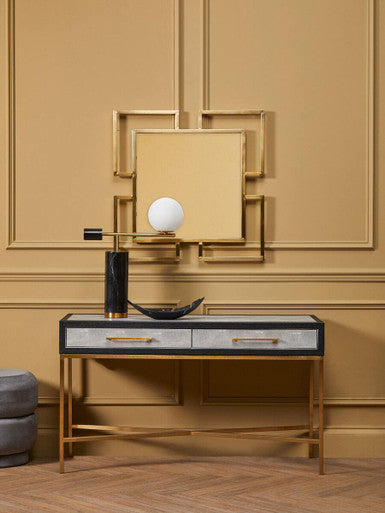 Decorative console table with a mirror and decorative items against a beige wall.