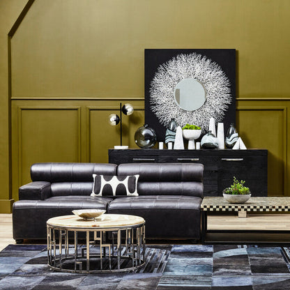 Modern living room with black leather sectional sofa, coffee table, and decorative wall art.