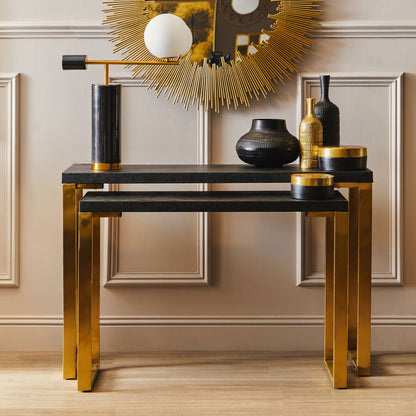 Decorative console table with gold and black accents against a neutral wall.