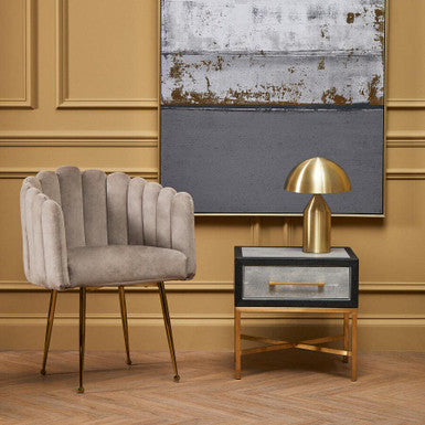 Modern interior with a gray chair, gold table lamp, and abstract painting on a beige wall.
