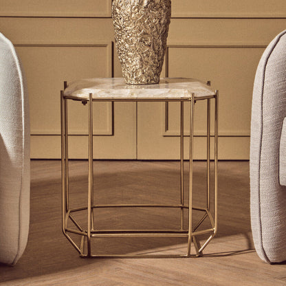 Gold side table with marble top and textured gold vase against a beige wall.