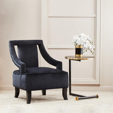 Black armchair in a stylish room with a side table and wall sconce.