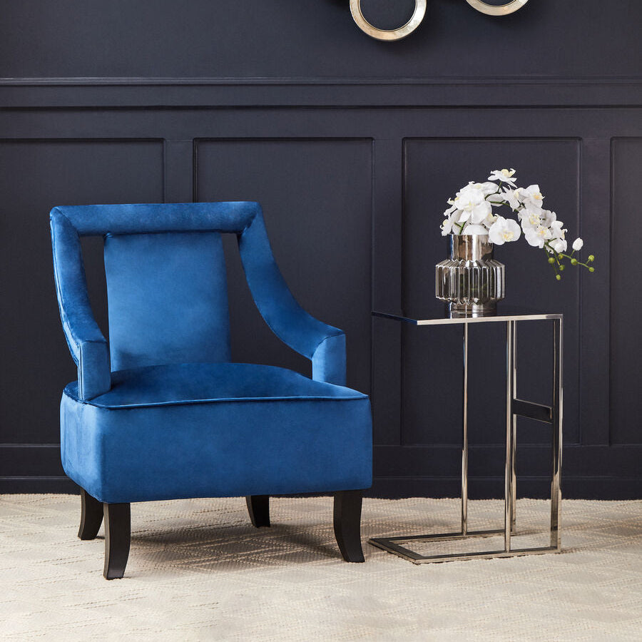 Blue armchair in a room with a decorative wall piece and a small table with flowers.