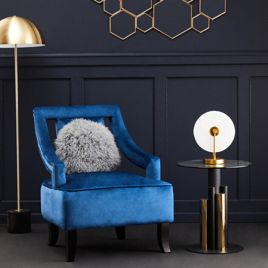 Blue armchair with a gray cushion in a room with geometric wall art and gold lamps.