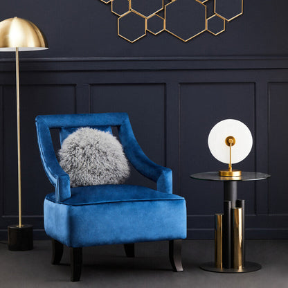 Blue armchair with a gray cushion in a room with geometric wall art and gold lamps.