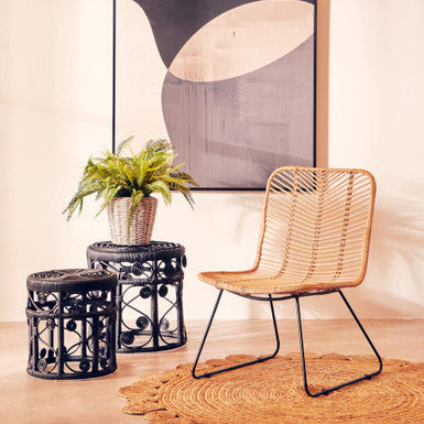 Wicker chair and side tables with a abstract painting in a room.