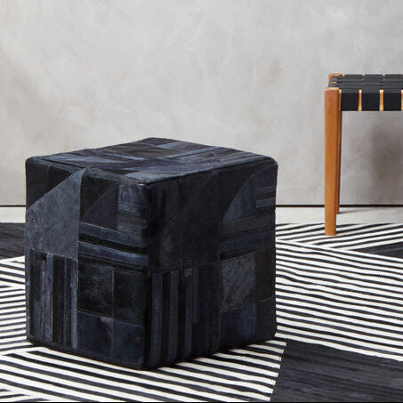 Modern interior with a geometric-patterned rug, black ottoman, and striped bench.