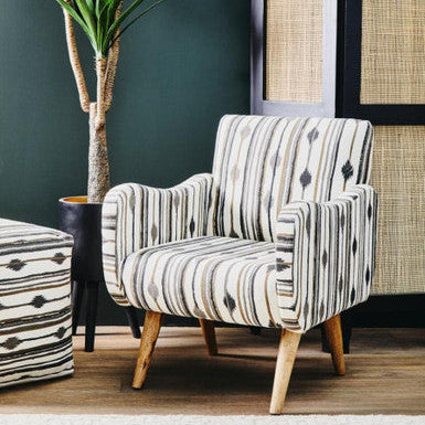 Patterned armchair in a room with a dark green wall and decorative elements.