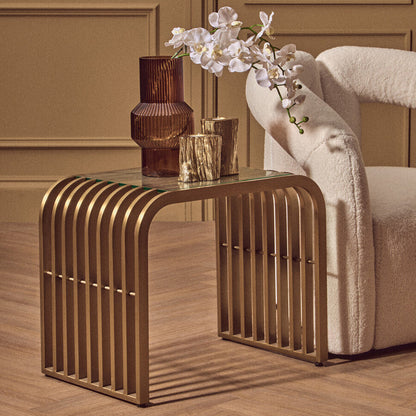 Gold side table with decorative items against a beige wall