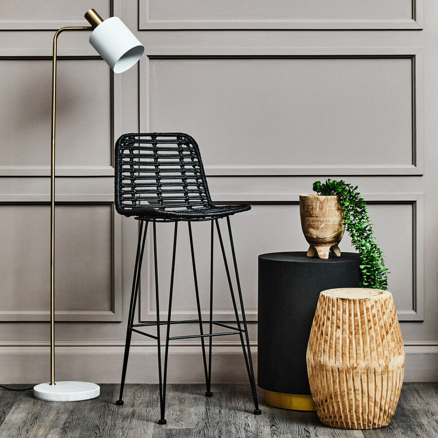 Modern interior with black bar stool, floor lamp, and decorative items against a gray paneled wall.