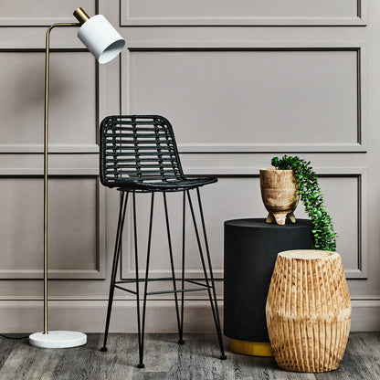 Modern interior with black bar stool, floor lamp, and decorative items against a gray paneled wall.