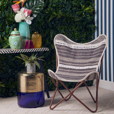 Patterned chair next to a small table with decorative items against a green wall.