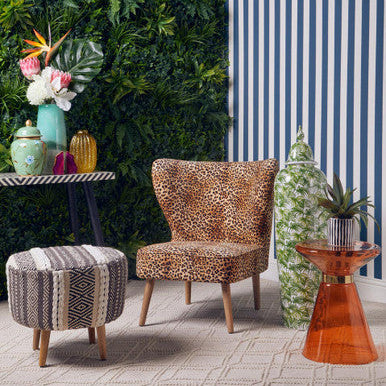 Leopard print chair with a striped wall and decorative plants in an outdoor setting
