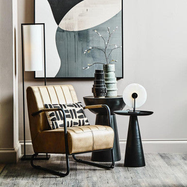 Modern living room with a beige armchair, side table, and abstract art on the wall.