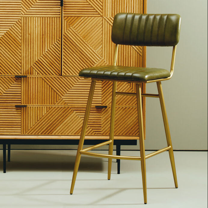 Wooden cabinet with geometric pattern and green bar stool against a light green wall.