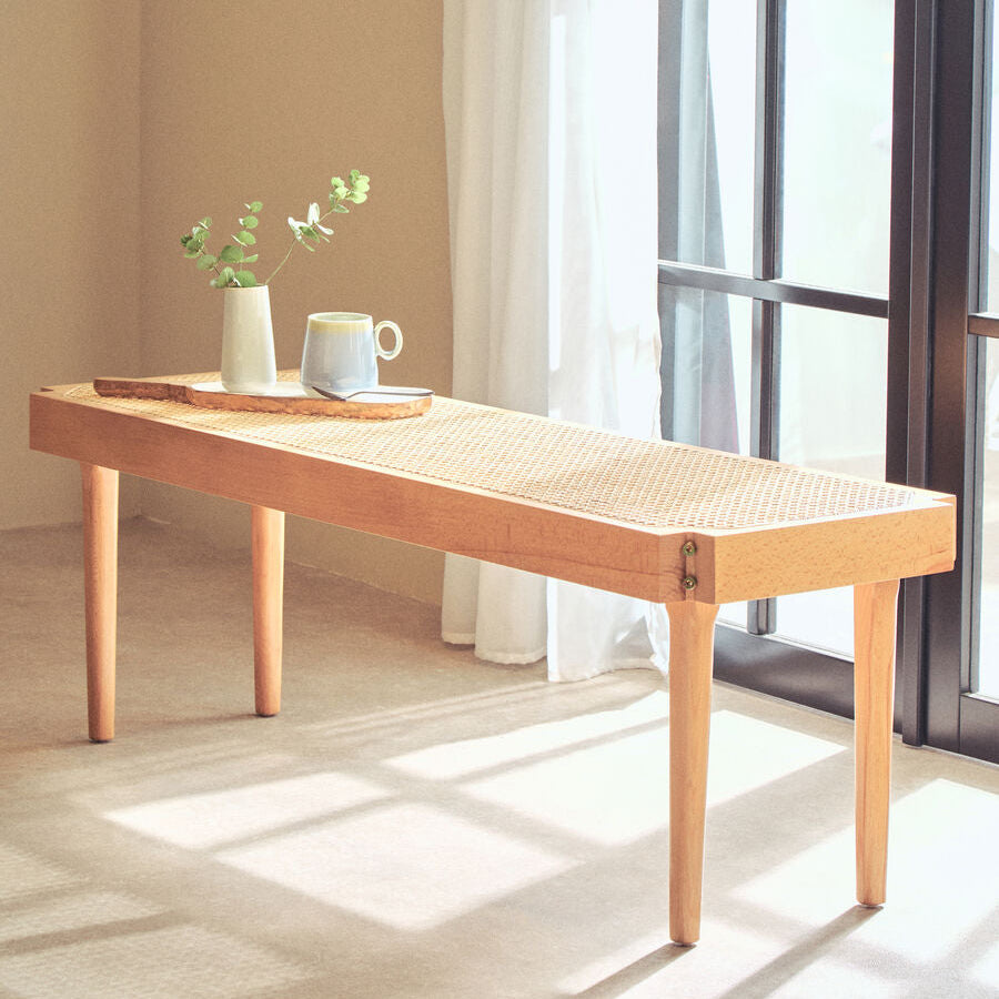 Wooden coffee table with a cup and vase in a bright room with large windows.