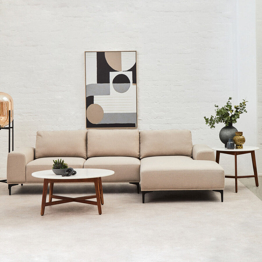 Modern living room with a beige sectional sofa, coffee table, and abstract art on the wall.