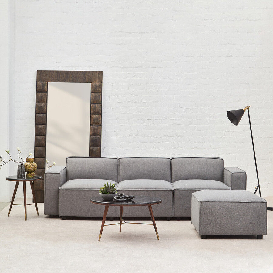 Gray sectional sofa in a modern living room with a mirror and lamp.