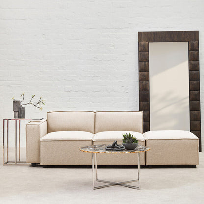 Beige sofa with a coffee table and decorative items against a light brick wall.