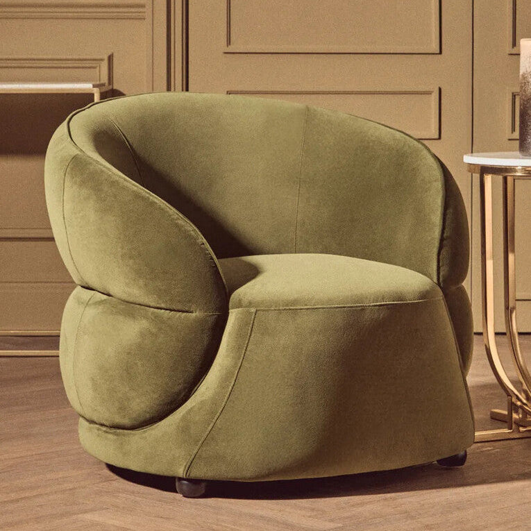 Green armchair in a room with a gold side table and decorative elements.