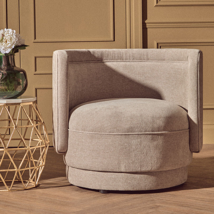Beige swivel chair in a room with wooden flooring and paneling.