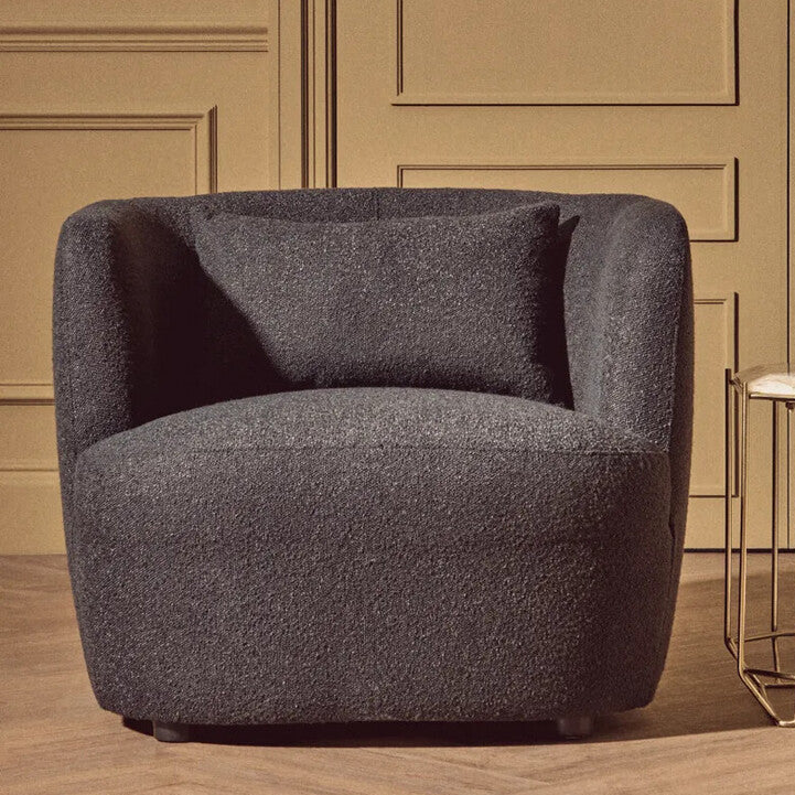 Gray armchair in a room with a gold wall and side table.