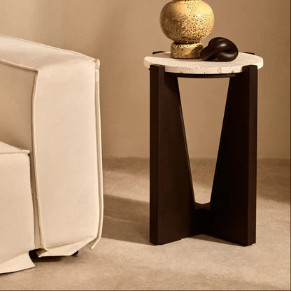 Modern side table with decorative items next to a beige sofa against a beige wall.