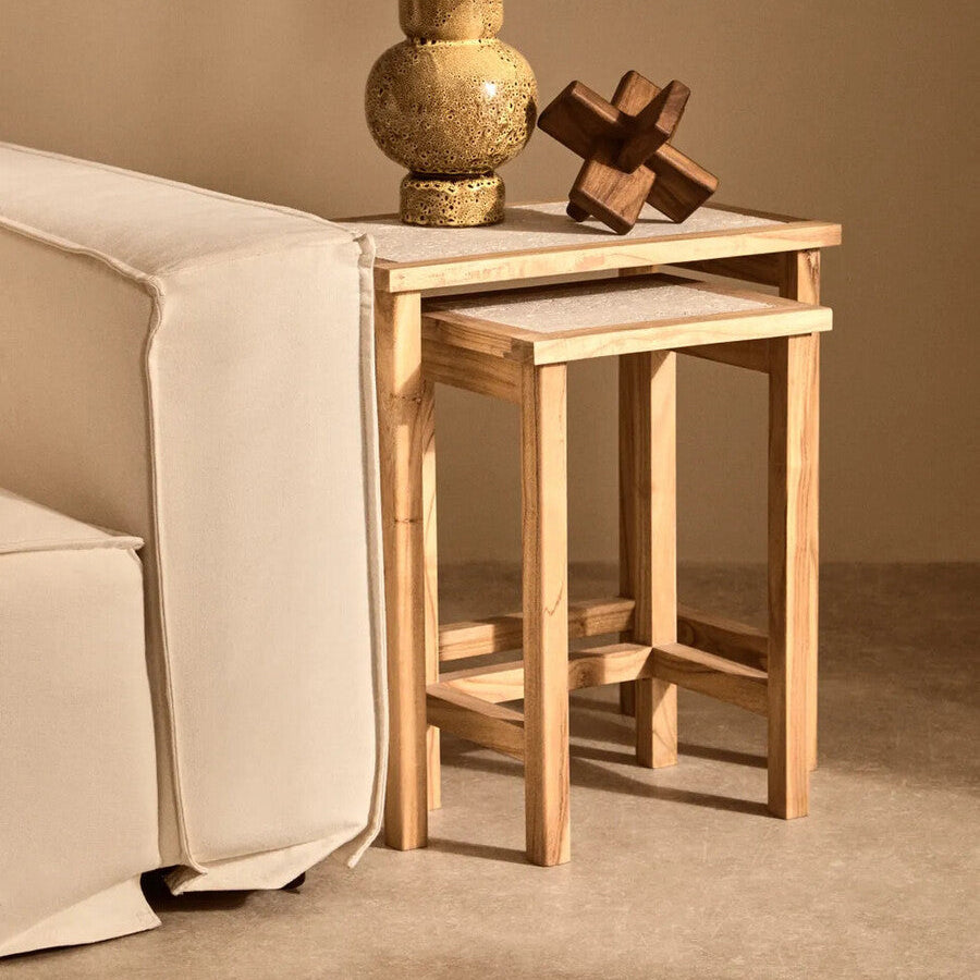 Wooden side table with a vase and decorative item against a beige wall.