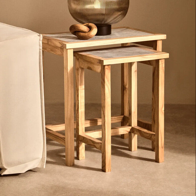Wooden nesting tables with a decorative vase on a beige sofa against a beige wall.