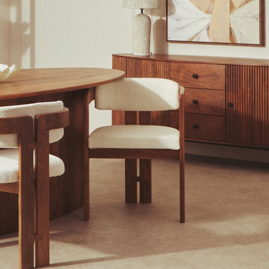 Dining room with wooden table, chairs, and sideboard in a well-lit room.